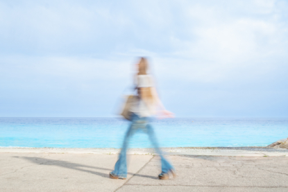 A lady with blue jeans walks by the blue bin near the blue sea below the blue sky. Her pace shows she is not feeling blue though (August 2017).