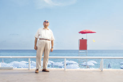 Walking along the promenade this man stopped to look at the beautiful classic hotel buildings across the street, next to the red life guard post on the beach (July 2017).
